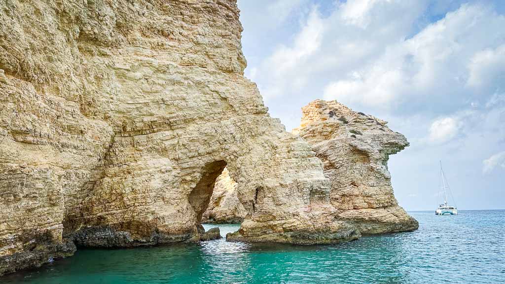 Faraglioni Kato Koufonisia. Natural arch over carved in a cliff over turquoise waters.