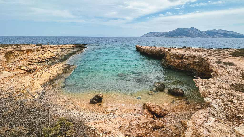 Inventure’s Bay Ano Koufonisia. A pebble beach surrounded by cliff side rocks and turquoise waters.
